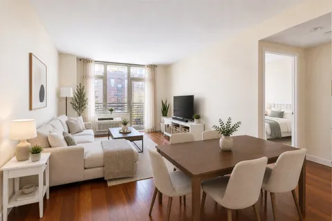 a living room with furniture wooden floor and a floor to ceiling window