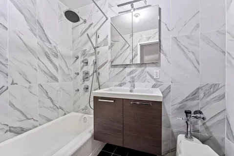 a bathroom with a sink and mirror with bathtub
