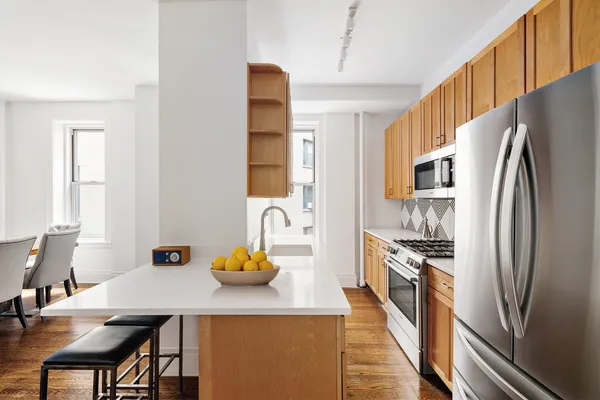 a kitchen with stainless steel appliances a dining table chairs and refrigerator