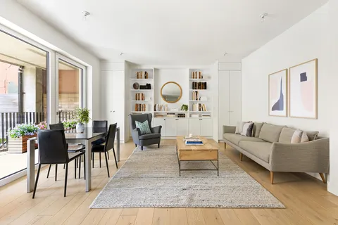 a living room with furniture a rug potted plant and a large window