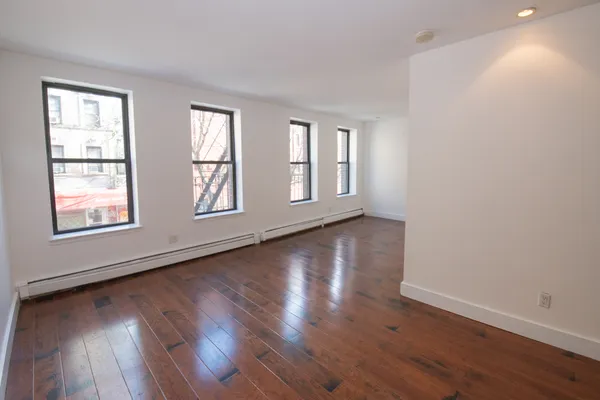 a view of an empty room with wooden floor and windows