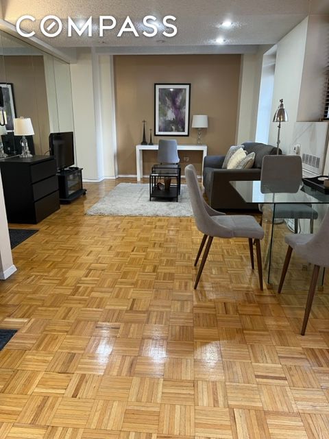 150 West 51st Street, Unit 1909 Manhattan, NY 10019 - Photo 2 of 12 a living room with furniture and a wooden floor