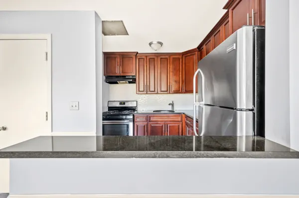 a kitchen with stainless steel appliances granite countertop a refrigerator a stove and a sink