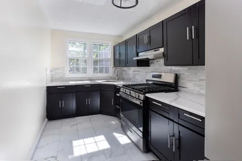 a kitchen with granite countertop a stove sink and cabinets
