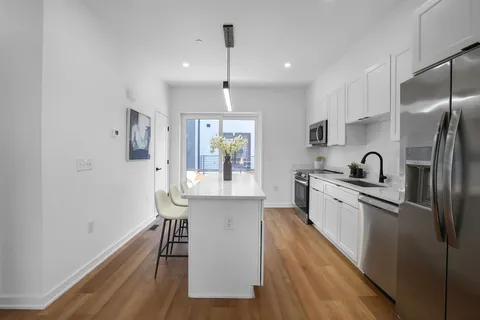 a kitchen with stainless steel appliances granite countertop a refrigerator a sink dishwasher a stove and white cabinets with wooden floor