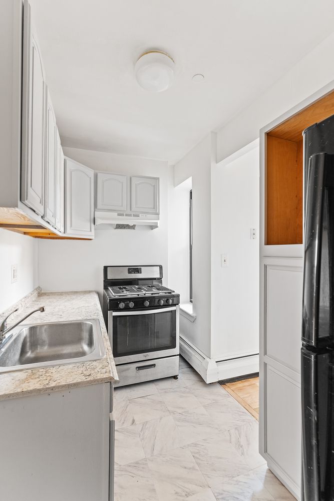 327 Pleasant Avenue, Unit 5B Manhattan, NY 10035 - Photo 4 of 5 a kitchen with a refrigerator sink and cabinets