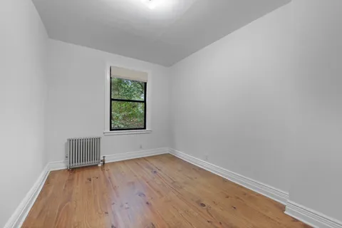 an empty room with wooden floor and window