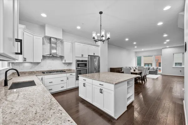 a kitchen that has a lot of cabinets a sink a stove and chairs in it