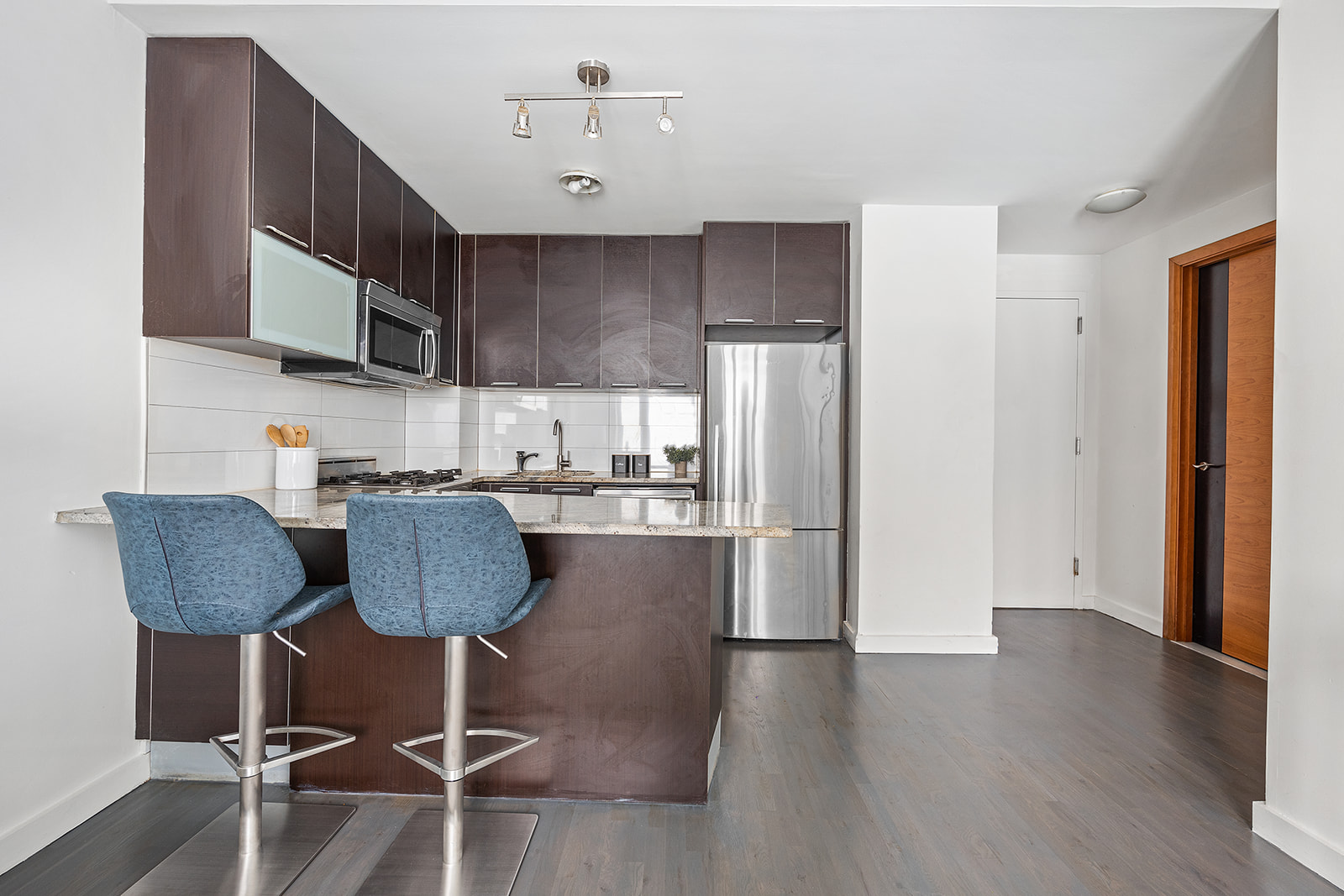 502 9th Avenue, Unit 4A Manhattan, NY 10018 - Photo 2 of 9 a kitchen with stainless steel appliances granite countertop a refrigerator a stove a sink dishwasher and white cabinets with wooden floor