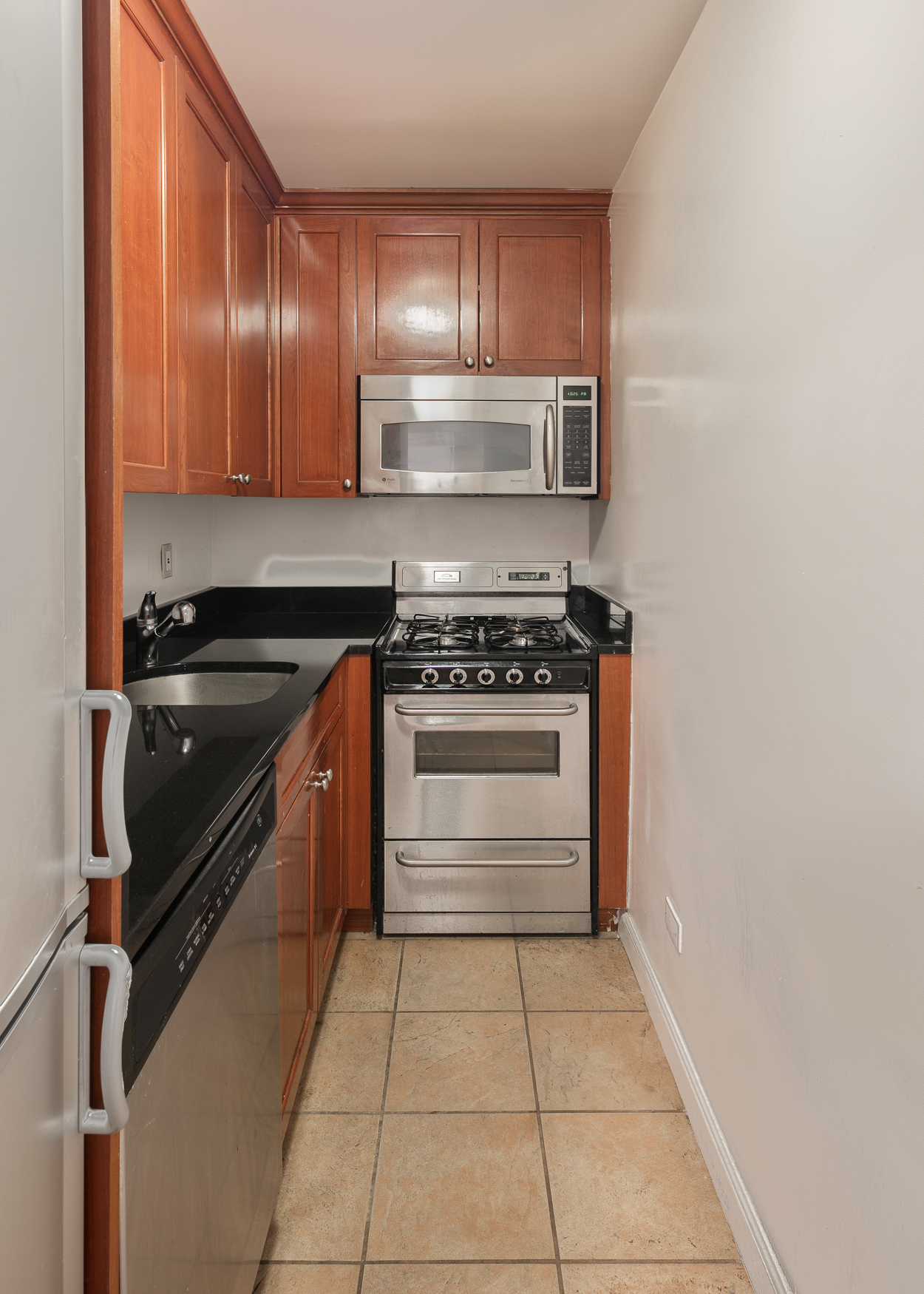 335 East 51st Street, Unit 2D Manhattan, NY 10022 - Photo 7 of 11 a kitchen with stainless steel appliances granite countertop a stove and a refrigerator