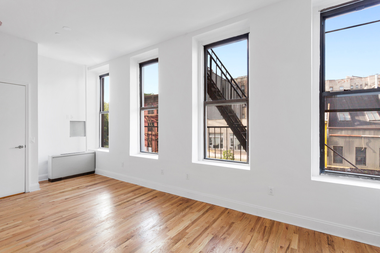 281 Grand Street, Unit 2R Manhattan, NY 10002 - Photo 7 of 11 a view of an empty room with wooden floor and a window