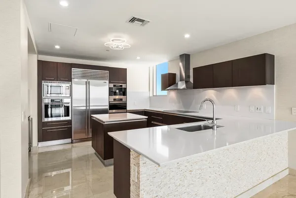 a kitchen with stainless steel appliances granite countertop a sink and a refrigerator