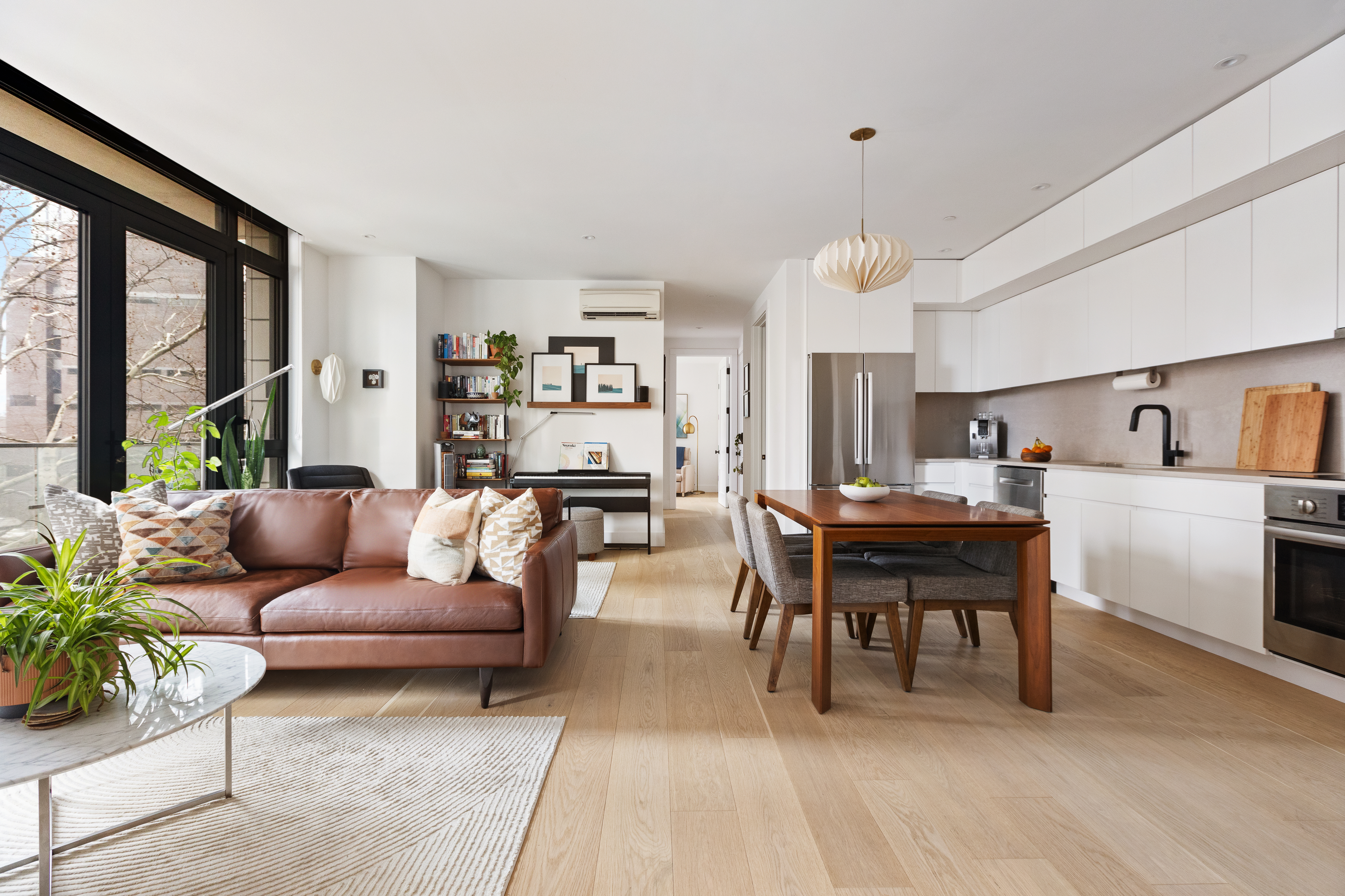 a living room with furniture a dining table and a large window