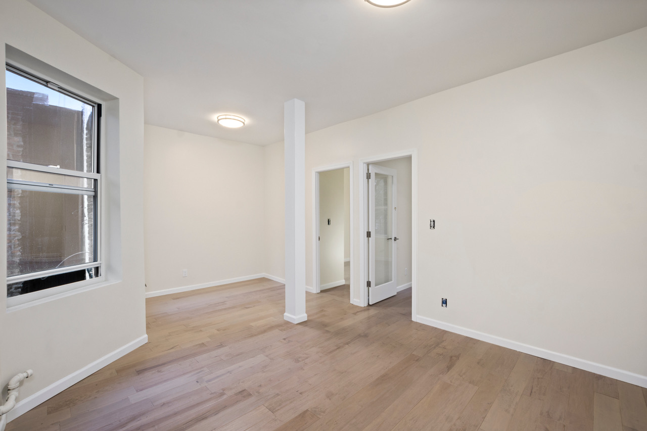 19 Christopher Street, Unit 9 Manhattan, NY 10014 - Photo 1 of 8 a view of an empty room with wooden floor and a window