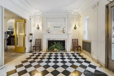 a living room with a black white checkered floor with a fireplace and rug