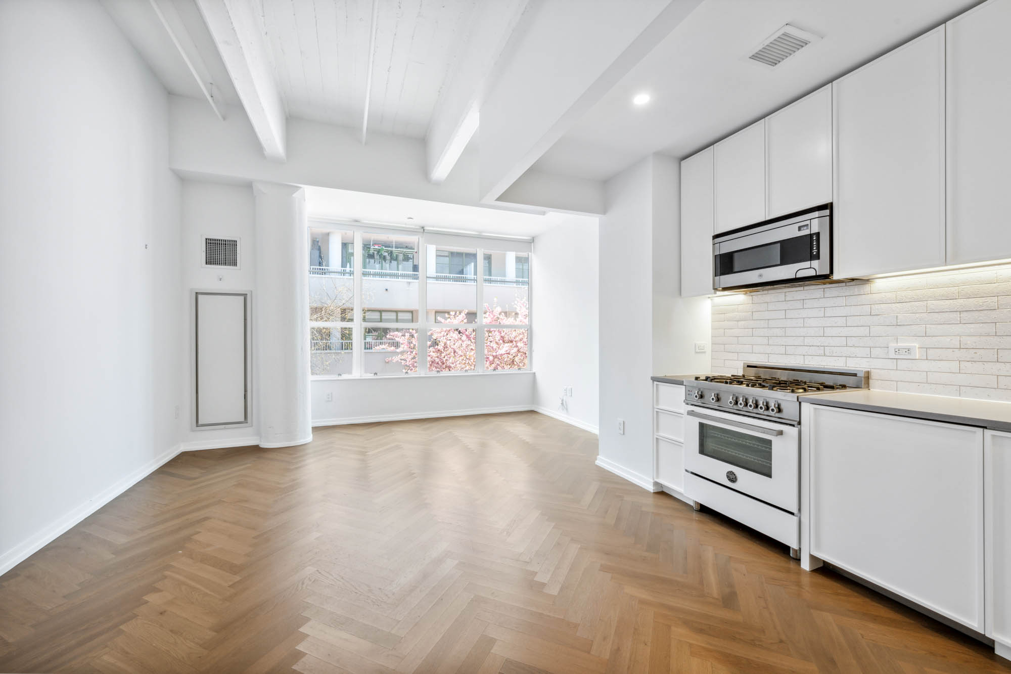 184 Kent Avenue, Unit D512 Brooklyn, NY 11249 - Photo 2 of 11 a kitchen with granite countertop a stove and a refrigerator