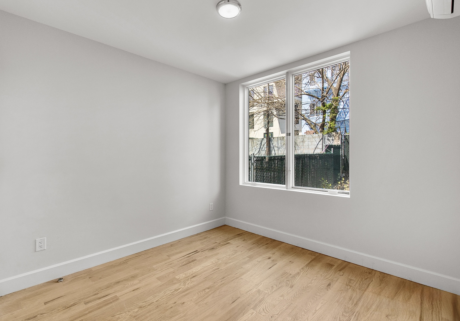 1098 Madison Street, Unit 1B Brooklyn, NY 11221 - Photo 7 of 16 a view of an empty room with wooden floor and a window