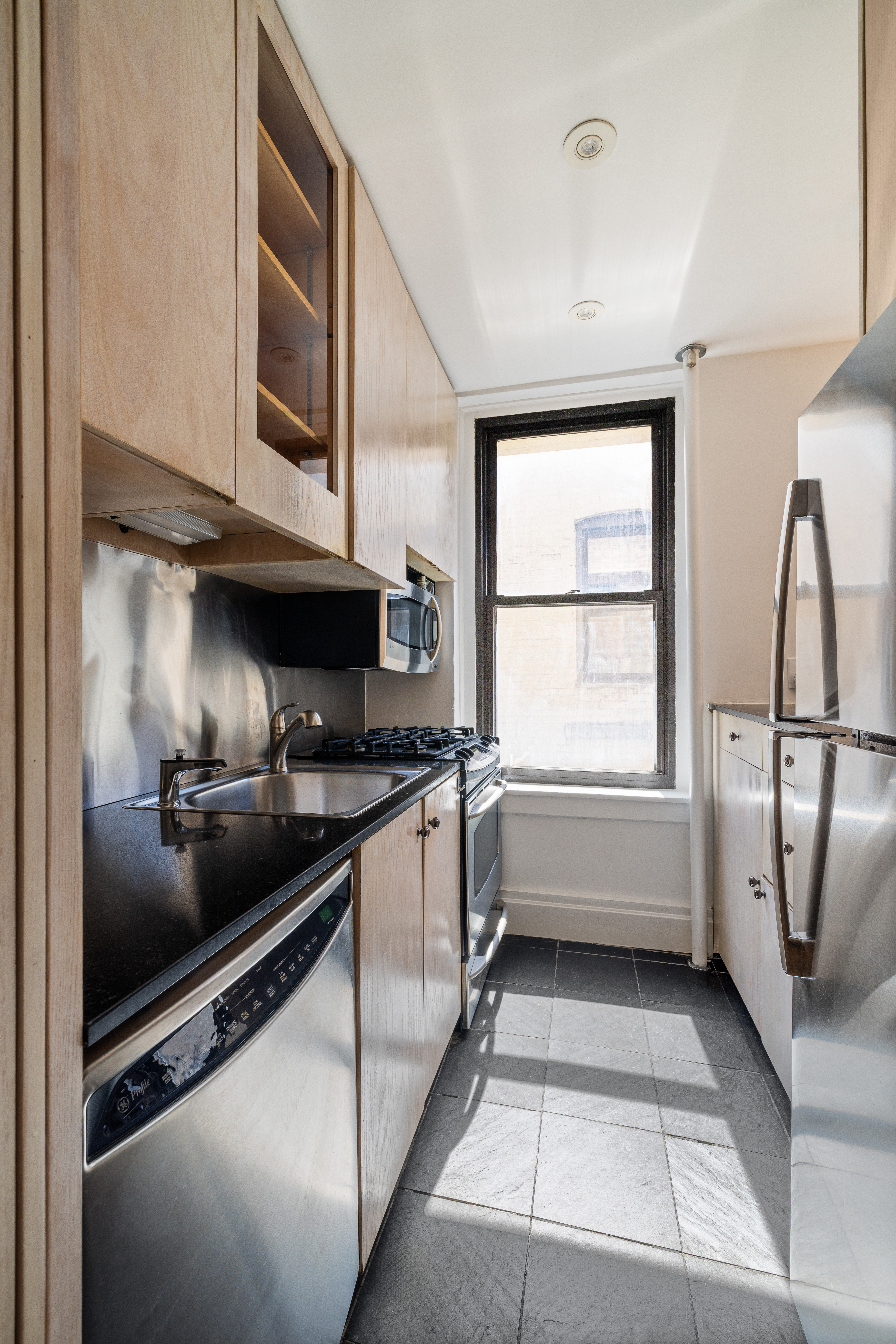 327 West 83rd Street, Unit 6B Manhattan, NY 10024 - Photo 7 of 13 a kitchen with stainless steel appliances granite countertop a sink and a microwave