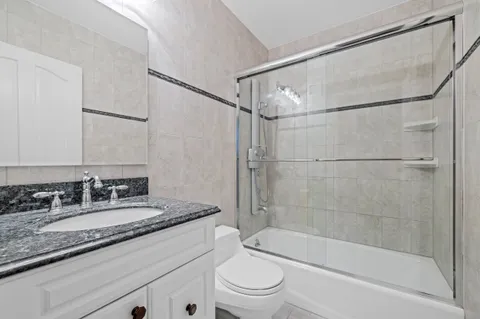 a bathroom with a granite countertop sink mirror toilet and bathtub