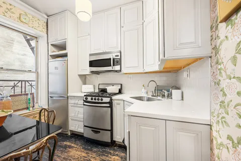 a kitchen with stainless steel appliances white cabinets and a stove top oven