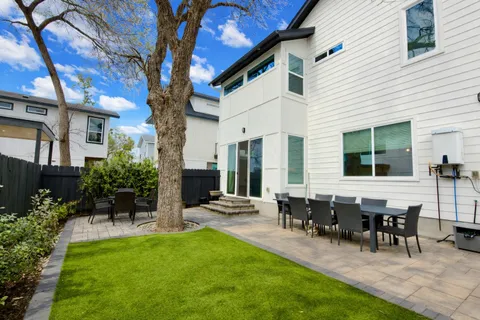 a view of a patio with table and chairs potted plants and large tree