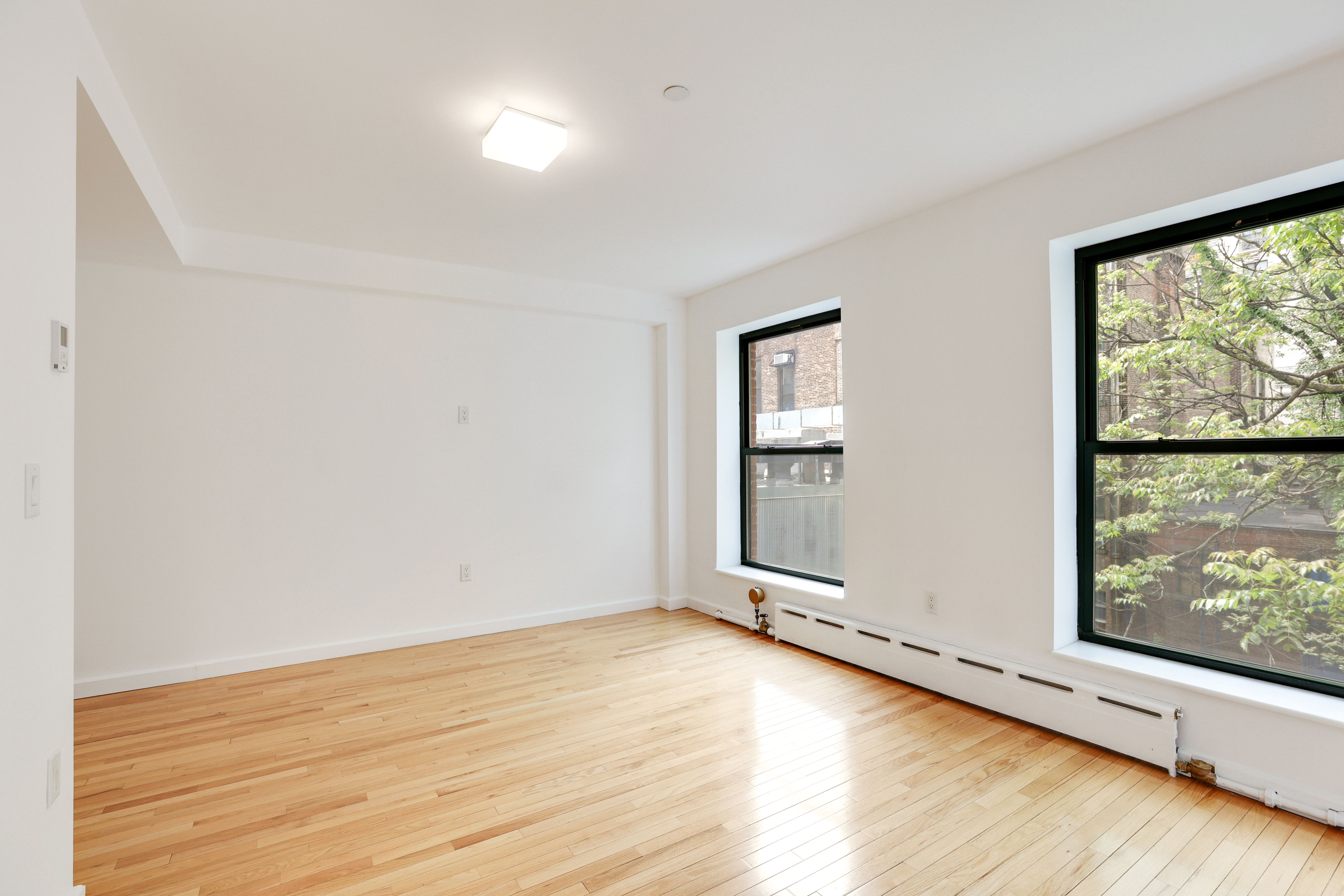 230 West 75th Street, Unit 4 Manhattan, NY 10023 - Photo 8 of 16 an empty room with wooden floor and windows