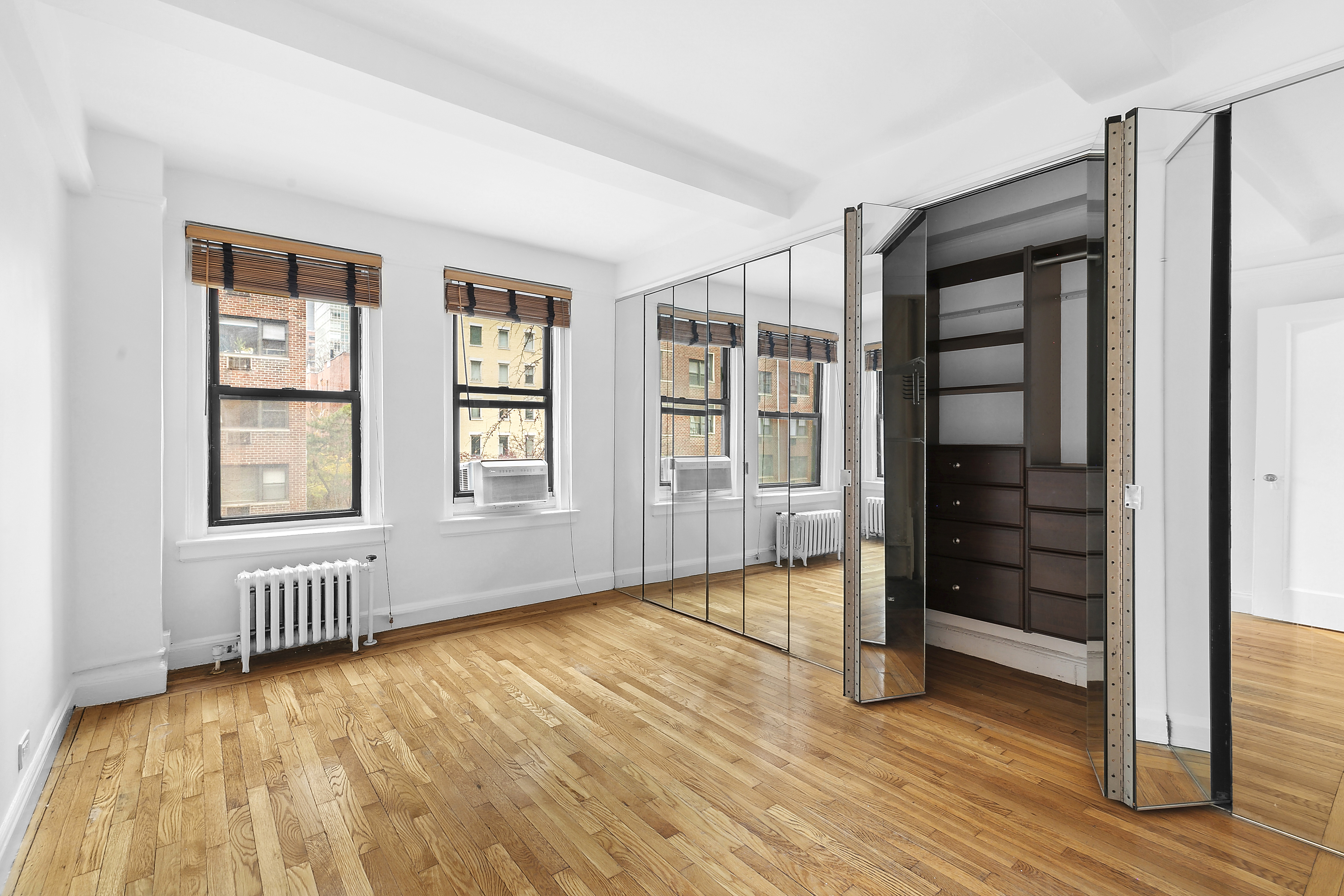 321 East 54th Street, Unit 4A Manhattan, NY 10022 - Photo 4 of 9 an empty room with wooden floor closet and windows