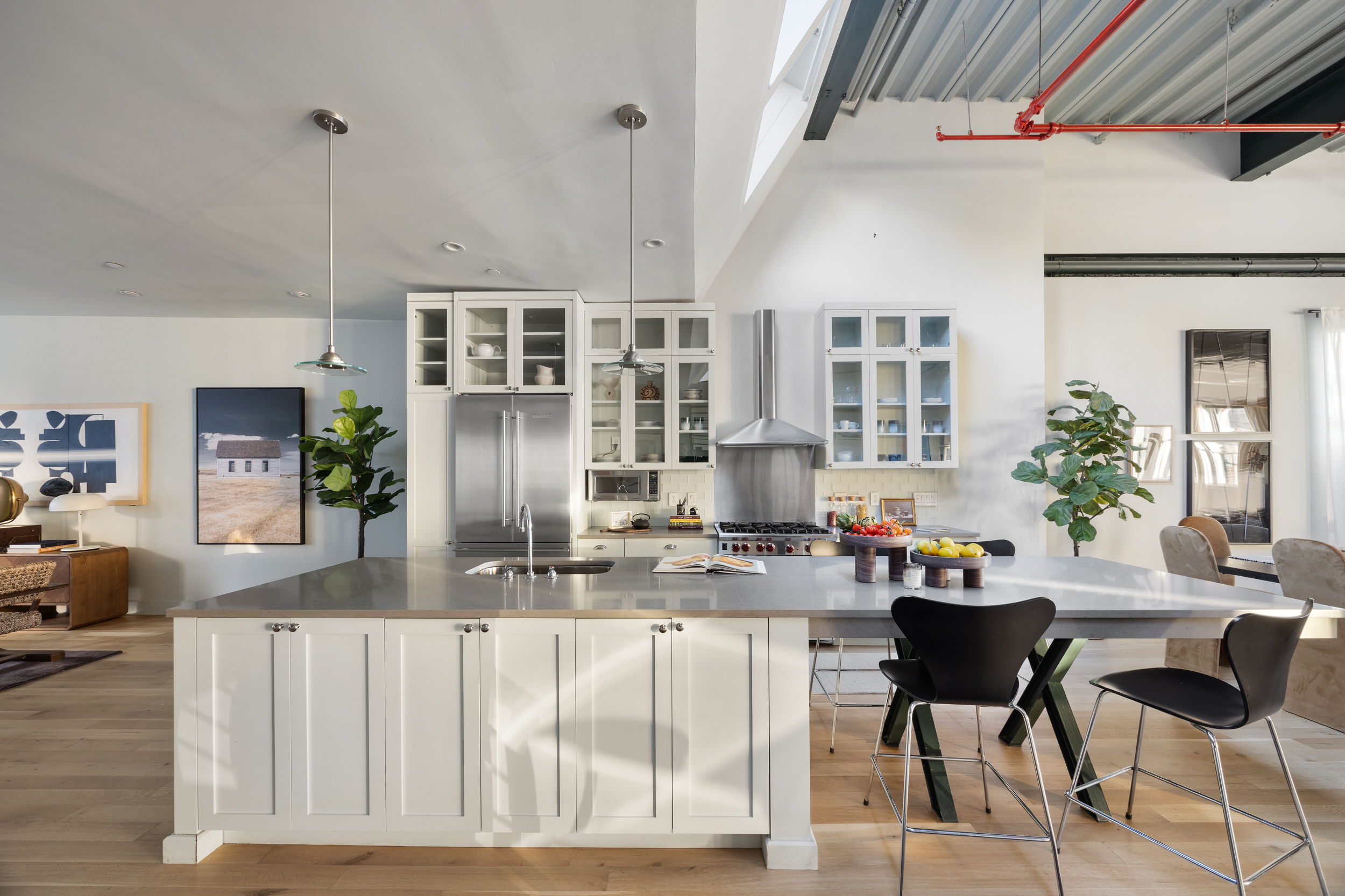 481 Washington Street, Unit PHS Manhattan, NY 10013 - Photo 10 of 20 a kitchen with stainless steel appliances kitchen island granite countertop a table chairs in it and wooden floors