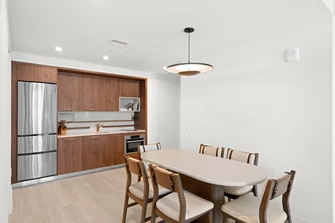 a kitchen with kitchen island a dining table chairs stainless steel appliances and cabinets