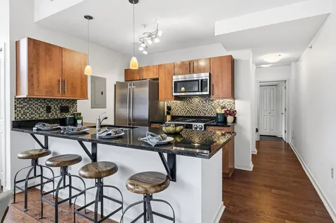 a kitchen with stainless steel appliances a stove a sink a refrigerator cabinets and dining table