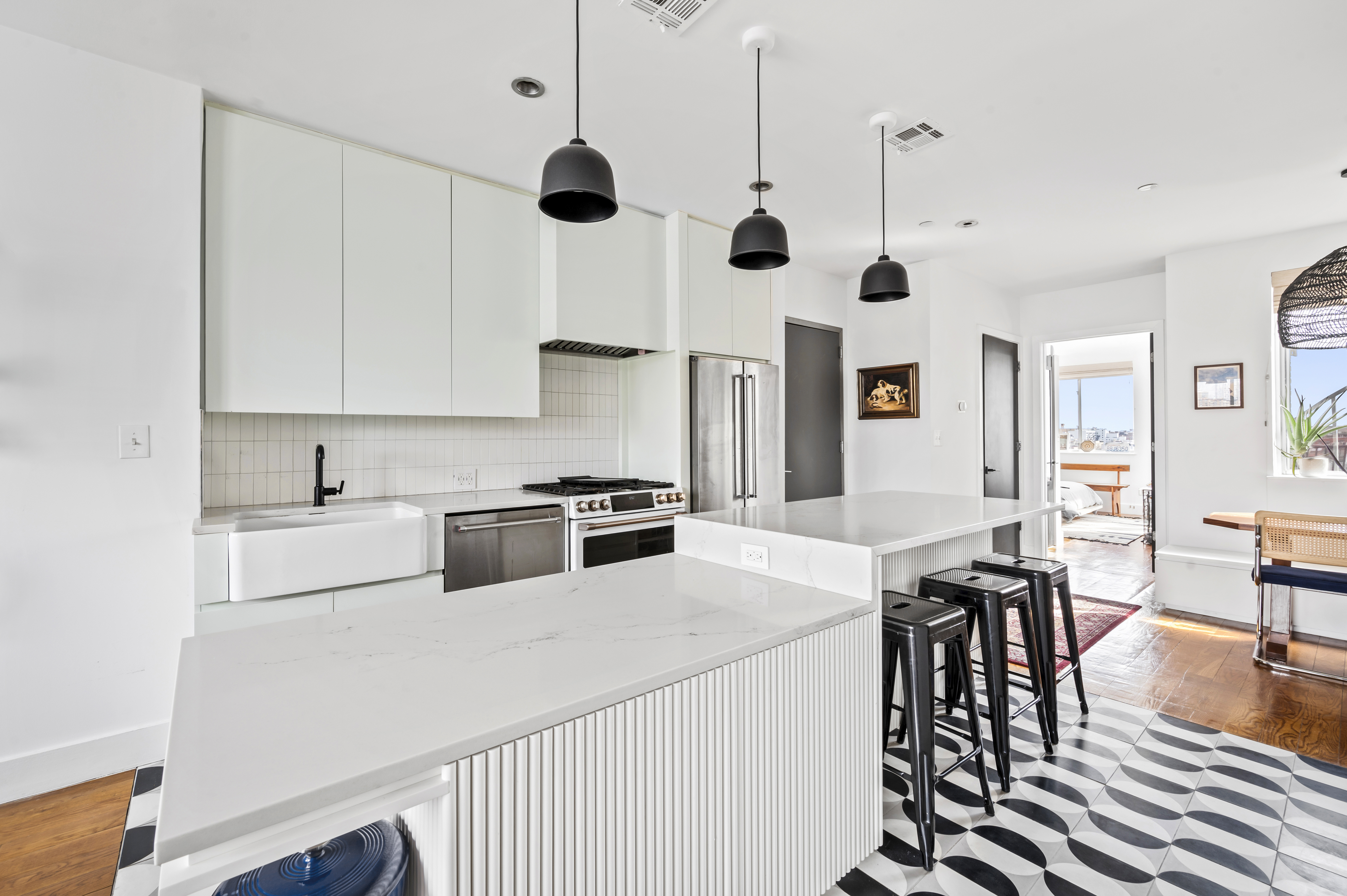 191 Spencer Street, Unit 9A Brooklyn, NY 11205 - Photo 4 of 10 a kitchen with stainless steel appliances a stove a sink a dining table and chairs with wooden floor