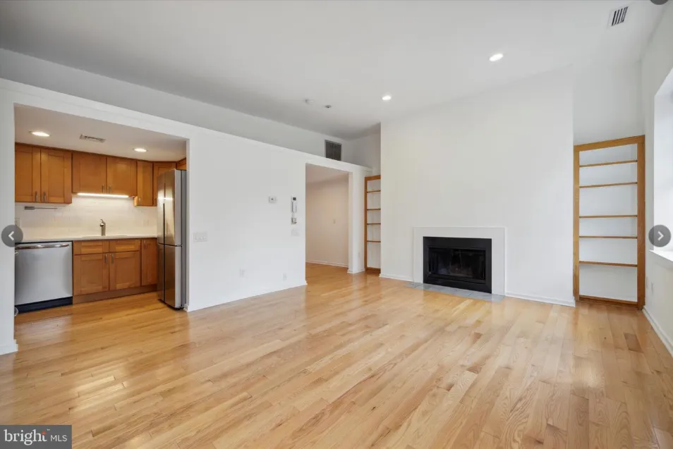 a view of empty room with wooden floor and fireplace
