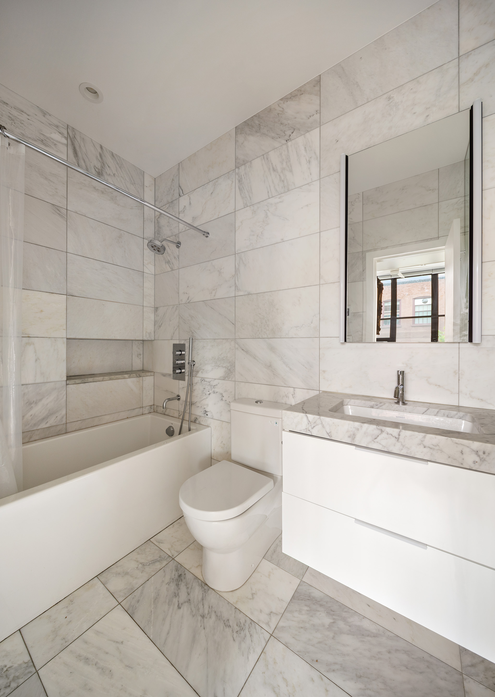 372 Dekalb Avenue, Unit 5J Brooklyn, NY 11205 - Photo 6 of 10 a bathroom with a granite countertop sink a toilet a mirror and bathtub