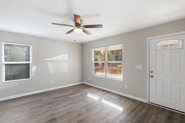 a view of empty room with wooden floor and fan