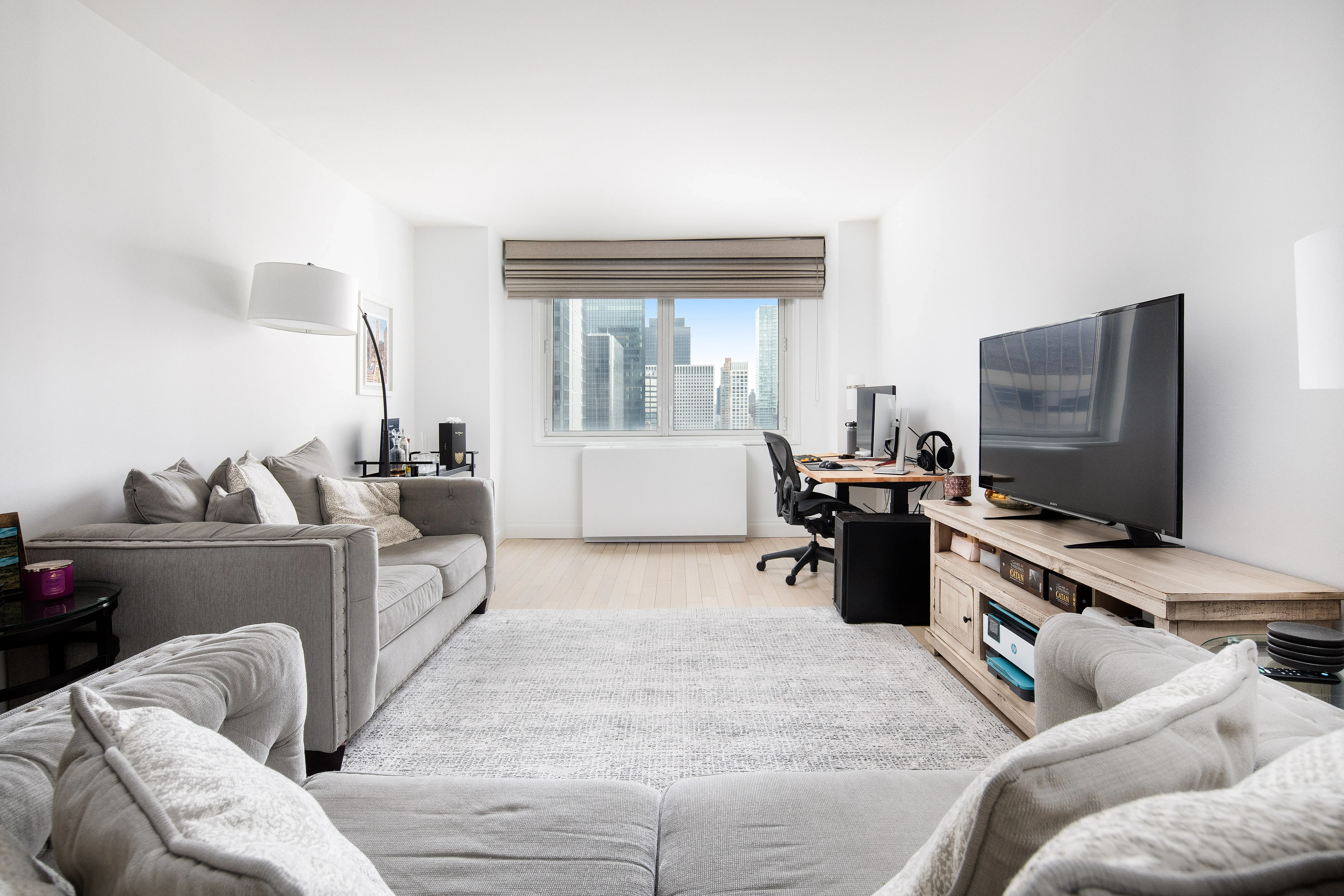 212 East 47th Street, Unit 21D Manhattan, NY 10017 - Photo 2 of 16 a living room with furniture and a flat screen tv