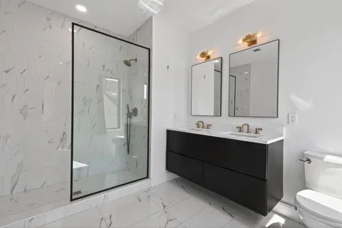 a bathroom with a double vanity sink mirror and shower