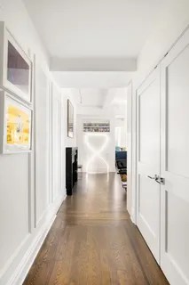 a view of a hallway with wooden floor and a living room