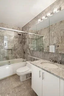 a bathroom with a granite countertop sink a toilet a mirror and bathtub