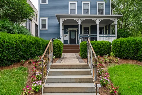 a front view of a house with potted plants and large windows