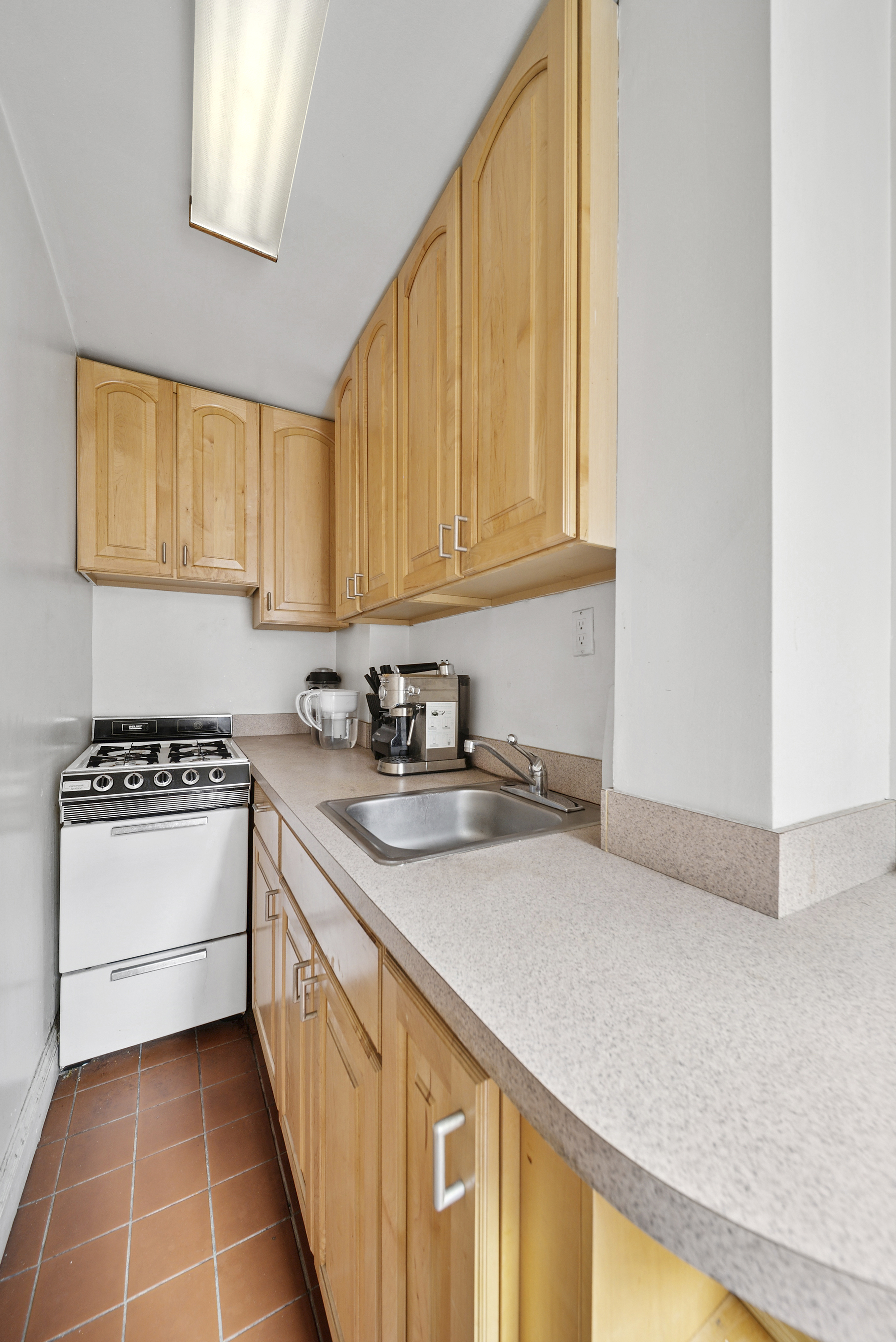 321 East 54th Street, Unit 6J Manhattan, NY 10022 - Photo 3 of 9 a kitchen with a sink a stove and cabinets