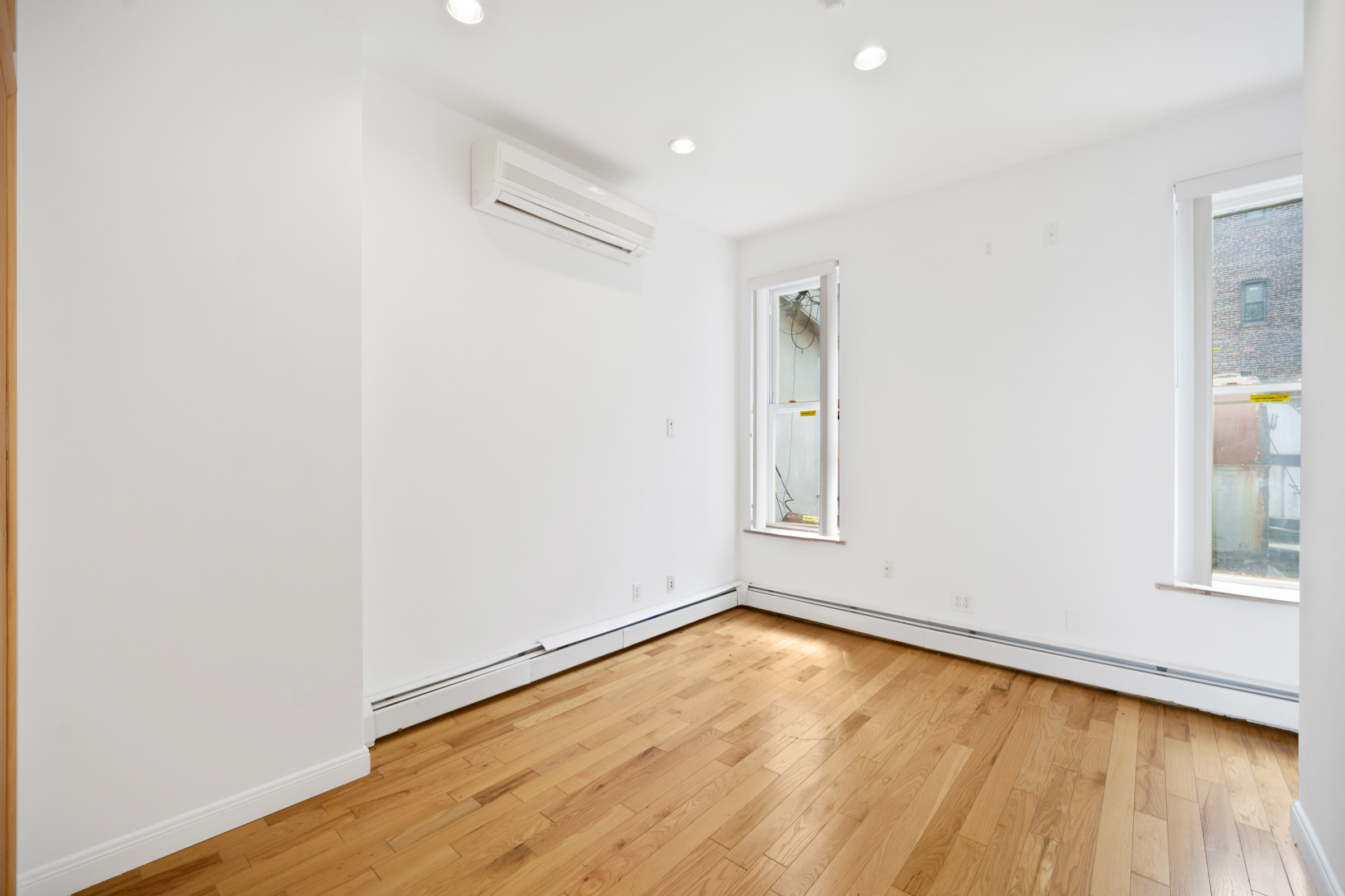 614 Eastern Parkway, Unit 2 Brooklyn, NY 11225 - Photo 4 of 6 an empty room with wooden floor and windows