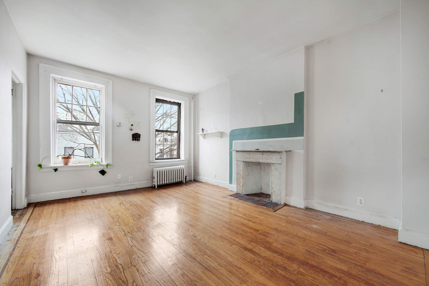 337 East 18th Street Manhattan, NY 10003 - Photo 9 of 16 an empty room with wooden floor fireplace and windows