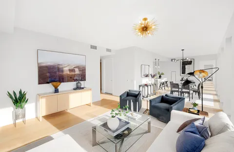 a living room with furniture a chandelier and a dining table