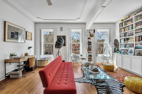 a living room with furniture a bookshelf and a wooden floor