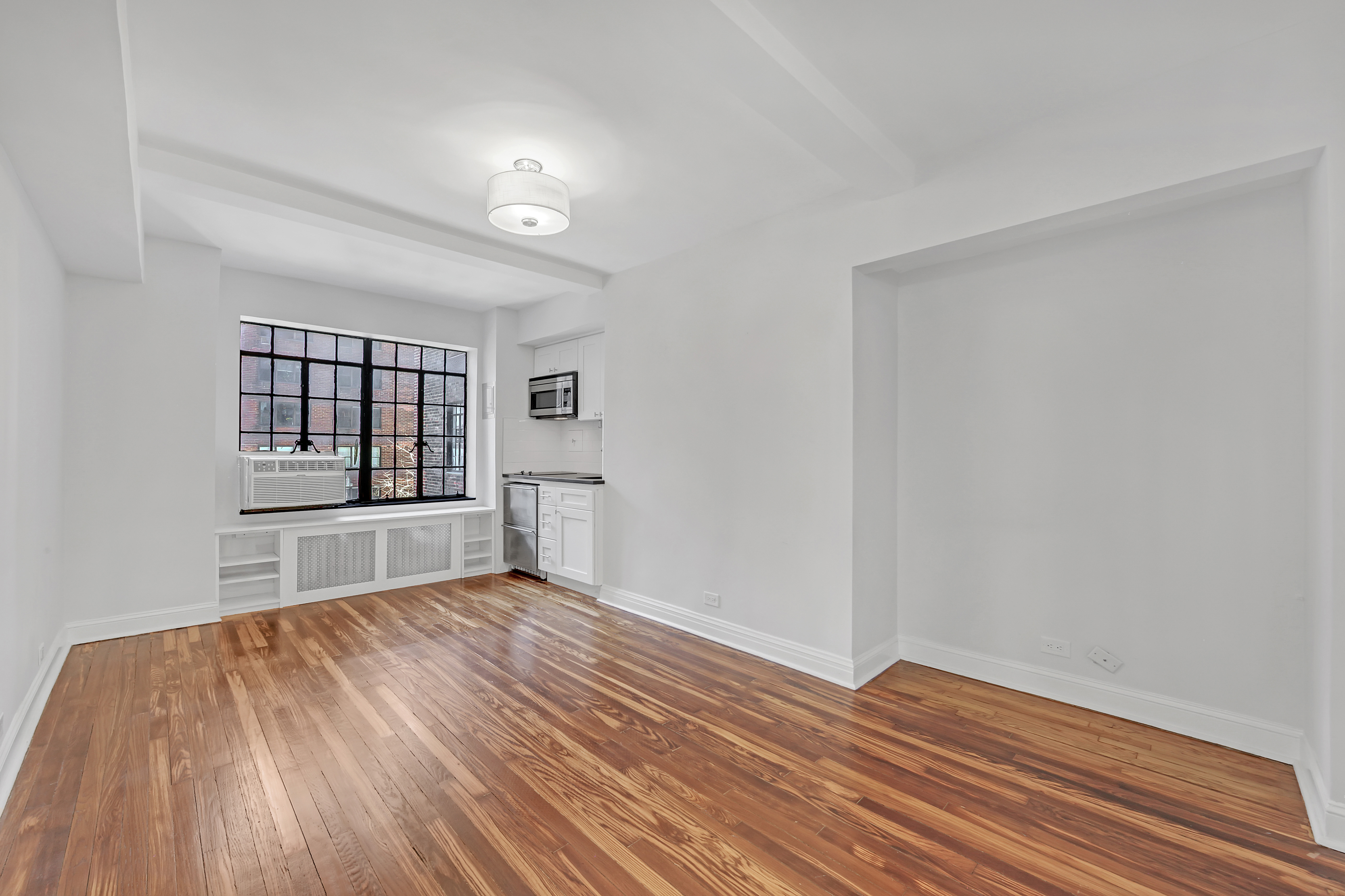 5 Tudor City Place, Unit 608 Manhattan, NY 10017 - Photo 2 of 12 wooden floor in an empty room with a window
