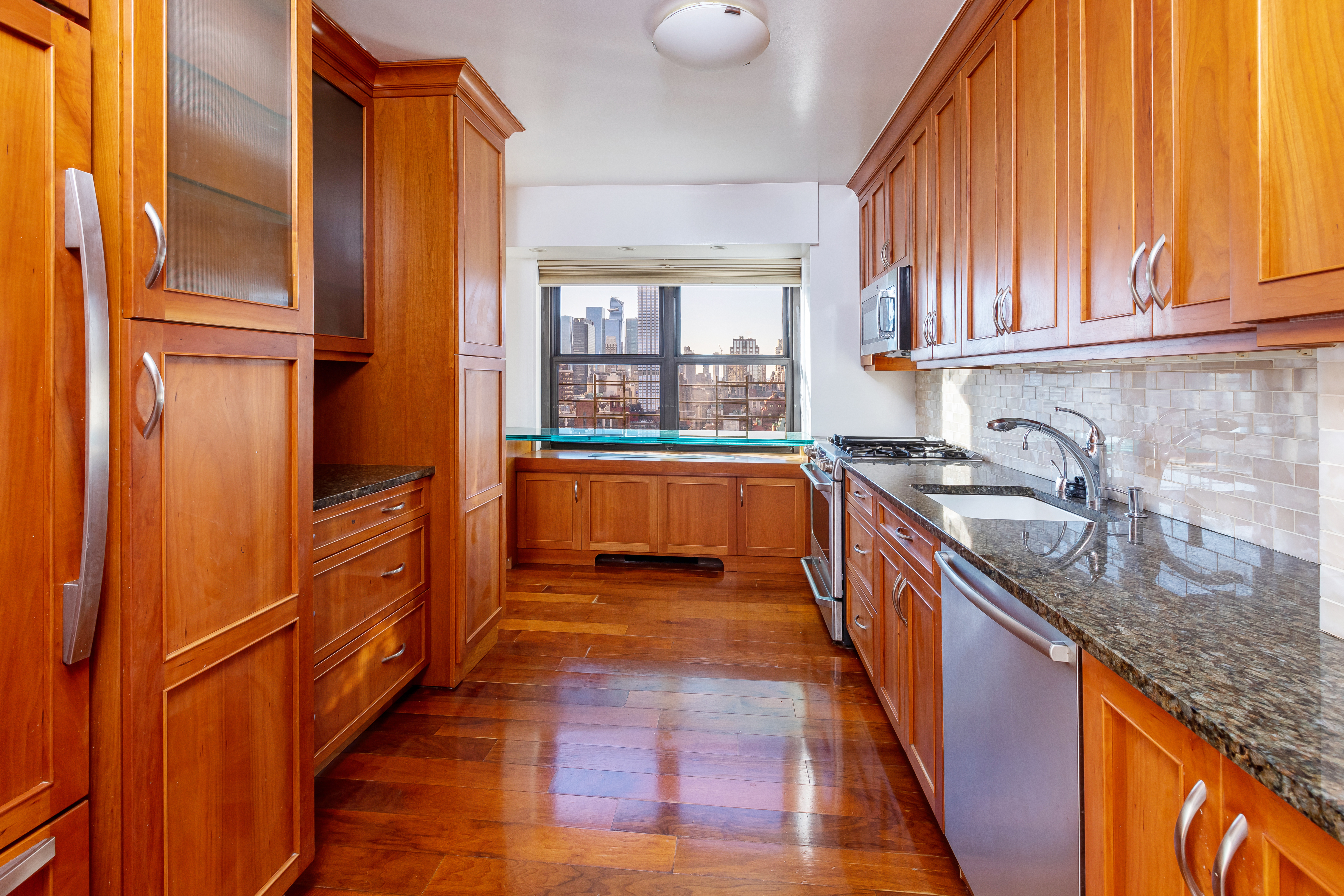 160 East 38th Street, Unit 32A Manhattan, NY 10016 - Photo 5 of 22 a kitchen with granite countertop a sink and wooden cabinets