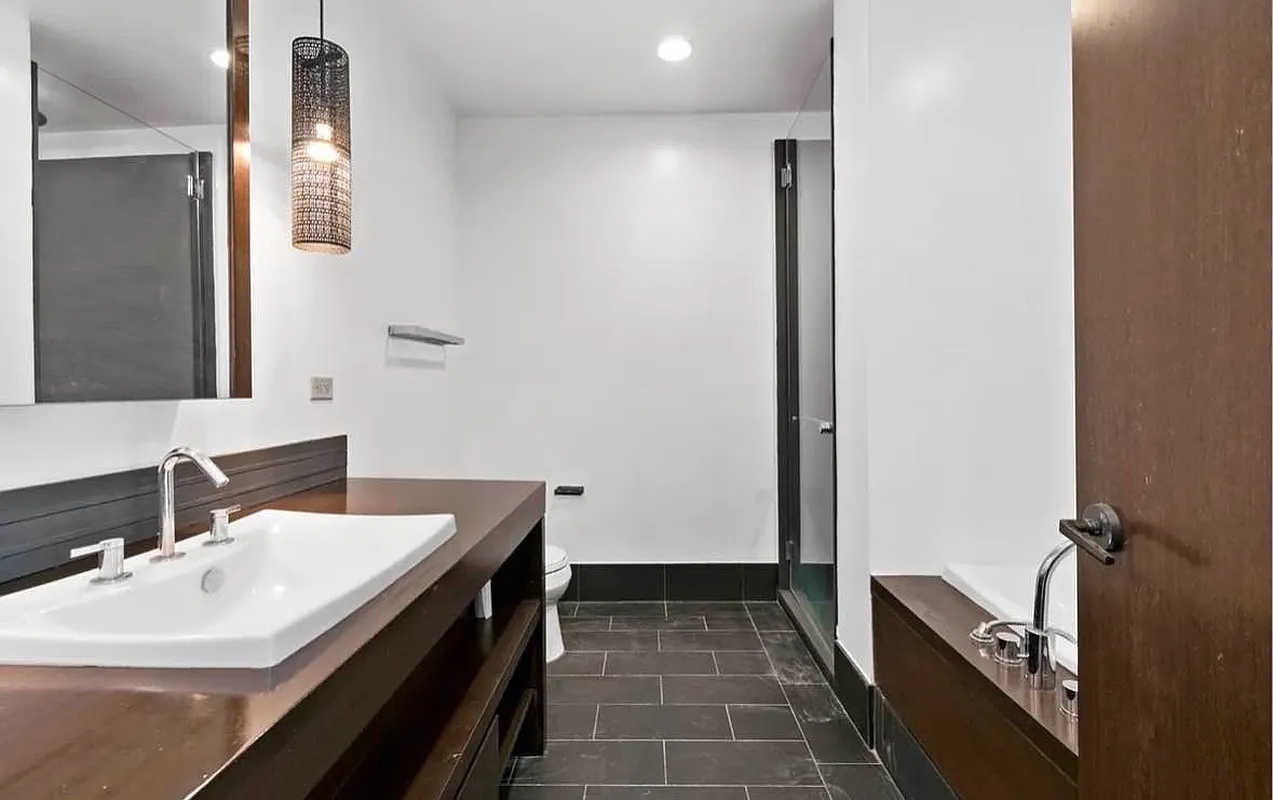 40 Broad Street, Unit 25C Manhattan, NY 10004 - Photo 5 of 10 a bathroom with a sink and a mirror