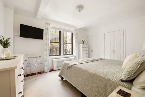 a spacious bedroom with a bed and a flat screen tv