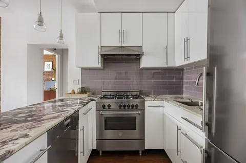 a kitchen with granite countertop white cabinets and white stove