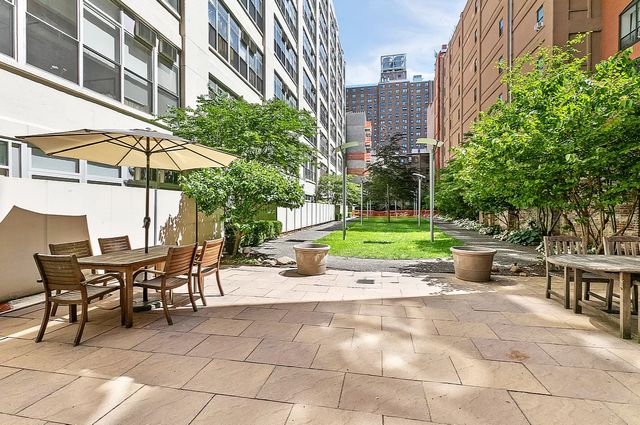 970 Kent Avenue, Unit 513 Brooklyn, NY 11205 - Photo 7 of 8 a view of a patio with a table and chairs under an umbrella